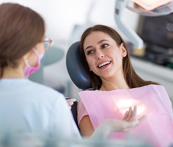 Woman in dental chair smiling at team member