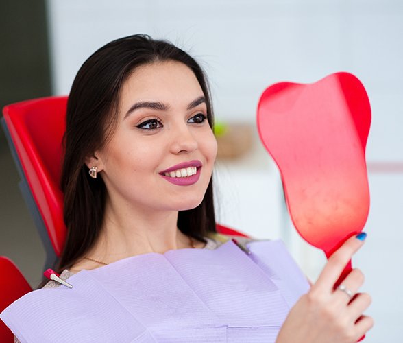 Woman looking at smile after metal free dental restorations