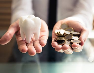 Hands holding tooth and coins for the cost of cosmetic dentistry in Wauwatosa 