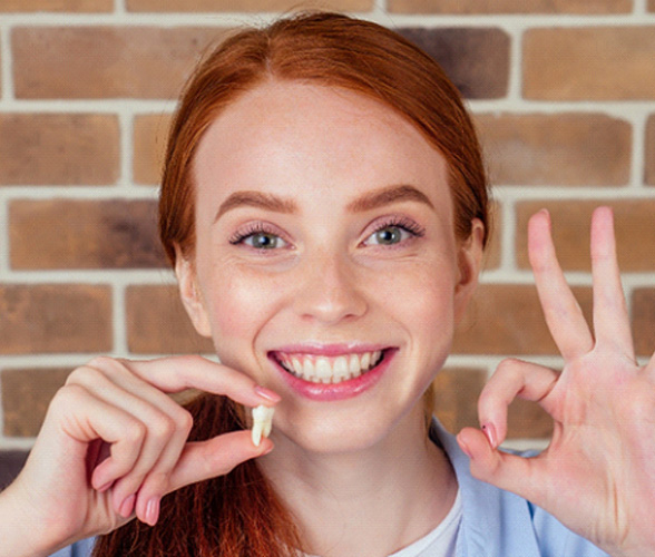 A woman holding a wisdom tooth between her fingers