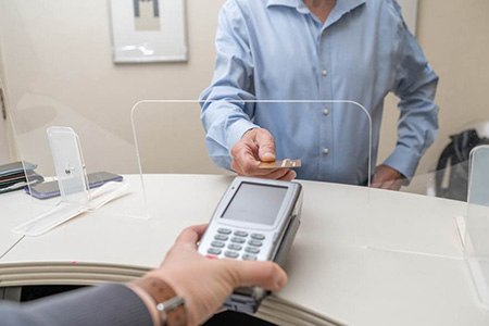 A man using a credit card to pay the cost of tooth extractions