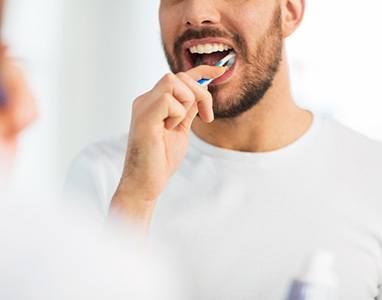 a man brushing teeth for dental implant care in Wauwatosa