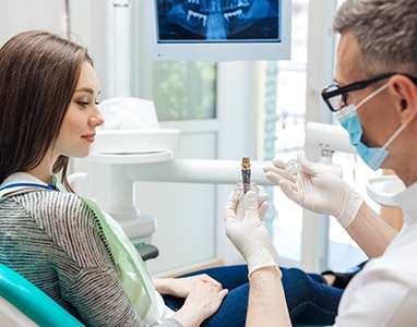 A young female listens to her dentist discuss the process of receiving dental implants in Wauwatosa