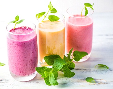 Series of fruit smoothies next to pile of mint leaves
