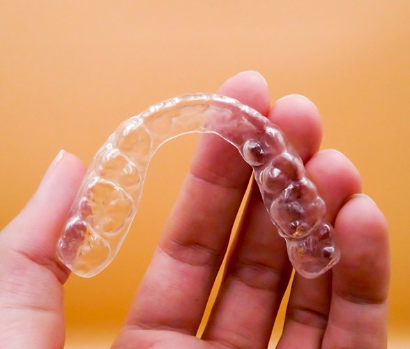 An up-close image of a person holding an Invisalign aligner in Wauwatosa